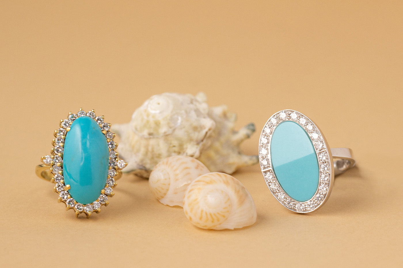 Two turquoise and diamond rings with a beige background and seashells.